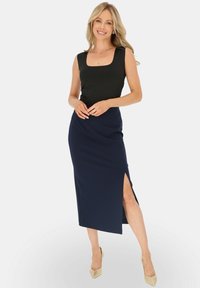 Czarny top bez rękawów w połączeniu z granatową midi spódnicą z bocznym rozcięciem. Całość dopełniają jasnobeżowe obcasy. Gładka tekstura materiału.