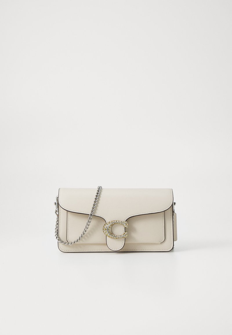 Beige leather shoulder bag with a silver chain strap, featuring a decorative circular clasp embellished with clear stones and rounded edges.