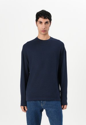 Navy long-sleeve t-shirt in cotton blend with a round neckline and relaxed fit. Pairs with blue jeans, smooth texture, and minimal detailing.