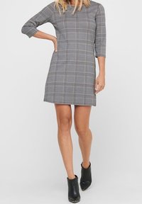 Robe à carreaux gris avec des manches trois-quarts et une coupe droite. Le tissu a une texture lisse, avec un motif à carreaux subtil.