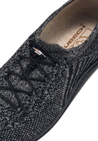 Czarno-szare dziane buty z teksturowanym wierzchem, okrągłym noskiem, czarnymi sznurowadłami i amortyzującą wkładką. Posiadają logo blisko sznurowadeł.