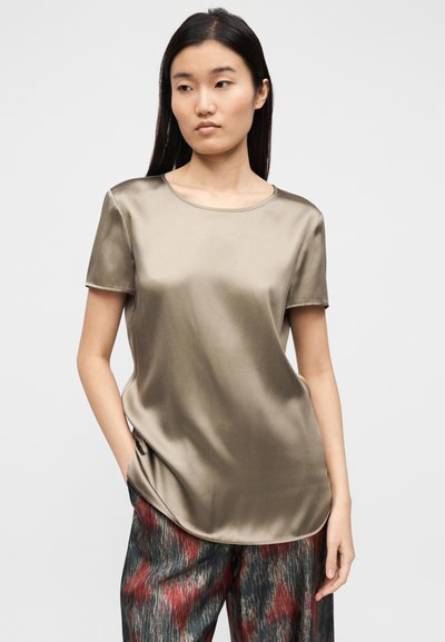 Top de cetim verde-oliva de manga curta, com decote redondo e ajuste descontraído, combinado com calças soltas estampadas.