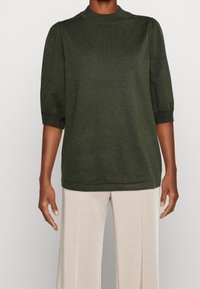 Pull vert foncé avec des manches courtes bouffantes, un col et des poignets côtelés, et une coupe décontractée, fabriqué en tissu tricoté doux.