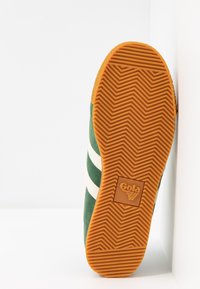 Grönt mocka sneakersula med ett fiskbensmönster, orange gummi och vita ränder. Gola-logotypen präglad i sules mitt.