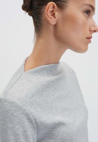 Maglione grigio a coste con colletto alto e finitura testurizzata, con cuciture sottili e silhouette aderente.