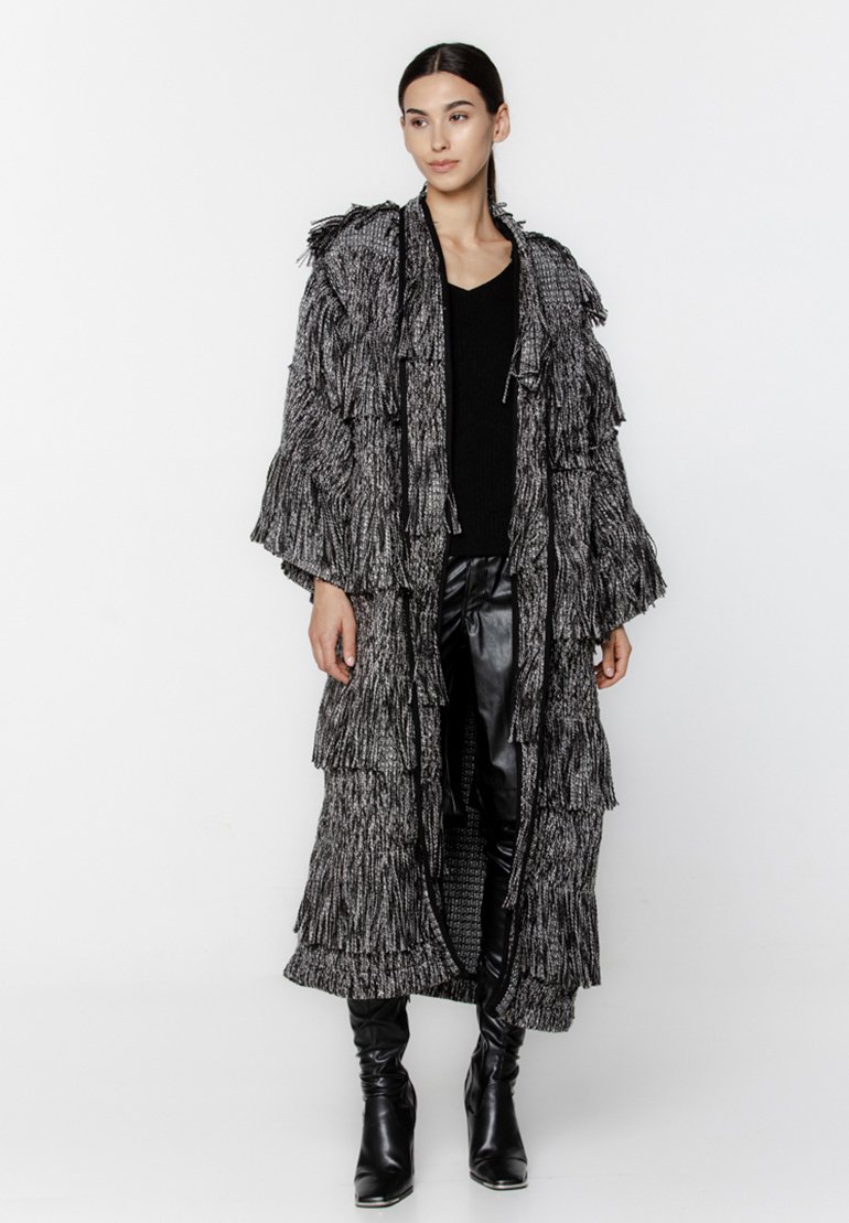 Długa frędzlowa kurtka w czarnym i szarym teksturowanym materiale, z kapturem, otwartym przodem i szerokimi rękawami, warstwowa z tierowanymi falbanami.