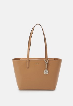 Sac cabas en cuir fauve avec double anse épaule et breloque logo circulaire dorée, marque embossée au centre devant.