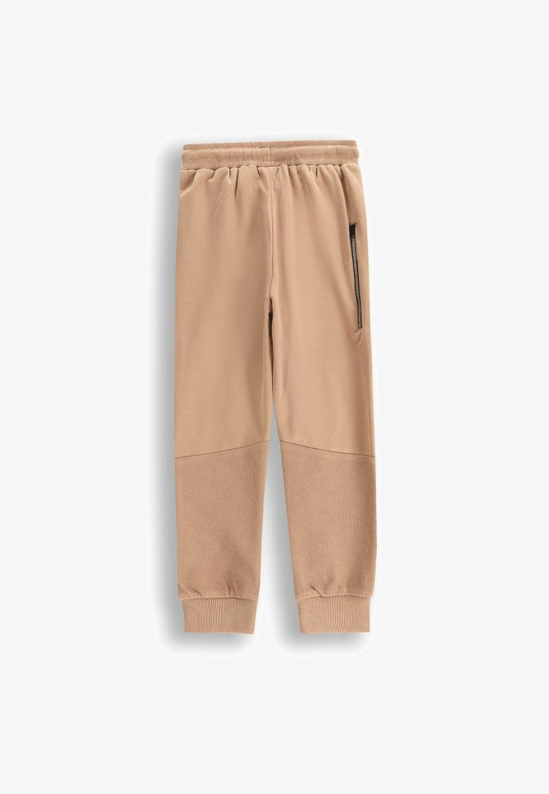 Beżowe dresy o gładkim materiale, z prążkowaną talią, boczną kieszenią na zamek oraz teksturowanymi panelami na dolnych nogawkach. Klasyczny krój, codzienny design.