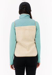 Fleece-voering vest met een lichtblauw gevoerd bovenstuk en een beige gestructureerde achterkant. Beschikt over een hoge kraag enzijnaad, ontworpen voor lagen.