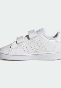 Białe dziecięce sneakersy z dwoma zapięciami na rzep, perforowaną wentylacją po bokach, teksturowaną podeszwą i wyściełanym kołnierzem.