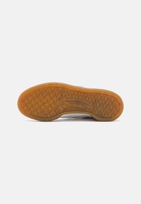 Outsole παπουτσιού Reebok, με υφή από καουτσούκ και διαμαντένιο σχέδιο, διαφανές χρώμα κεχριμπάρι και ανάγλυφη λεπτομέρεια λογοτύπου.