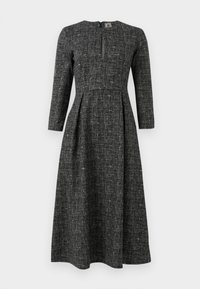 Svart-hvitt mønstret kjole med lange ermer, høy hals og splitt foran. Laget av strukturert stoff med en tettsittende bodice og utsvingt skjørt.
