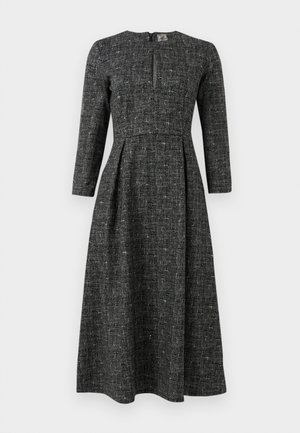 Black and white patterned dress with long sleeves, a high neckline, and a front slit. Made of textured fabric with a fitted bodice and flared skirt.