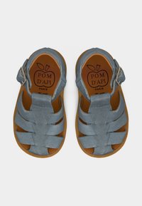 Μπλε παιδικά σανδάλια με λουράκια με αγκράφα και καφέ σόλες, με την επωνυμία Pom d'Api Paris στο εσωτερικό της σόλας.