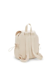 Beige Rucksack aus weichem Stoff mit runder Form. Verfügt über verstellbare Träger, einen oberen Griff und elastische Seitentaschen.