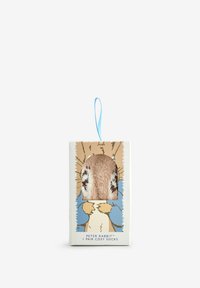 Zachte, lichtbruine, fuzzy sokken met donkere bruine vlekken, tentoongesteld in een rechthoekige doos met kleurrijke illustraties van Peter Rabbit en een blauwe strik.