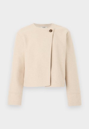 Krämfärgad, kort ulljacka med långa ärmar och asymmetrisk framstängning som fästs med en stor brun knapp.