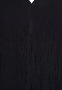 Black garment with a textured fabric featuring vertical creases and a V-shaped neckline. Overall smooth surface with a matte finish.