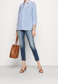 Blue and white striped button-up shirt, light blue jeans, brown handbag, and brown heeled sandals. Casual outfit with a relaxed fit.