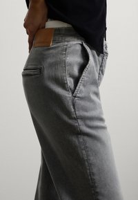 Grijze denim jeans met een gladde textuur, voorzien van een leren label met de tekst "STEFANEL" aan de achterkant, en standaard zijzakken.