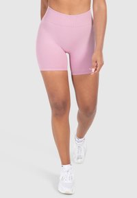 Roze hoge taille shorts gemaakt van rekbare stof met een gladde textuur, met een getailleerd ontwerp dat tot halverwege de bovenbenen komt, gecombineerd met witte sneakers.