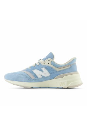 Lichtblauwe en beige New Balance sneaker met witte veters en een gevoerde zool, van opzij getoond op een witte achtergrond.