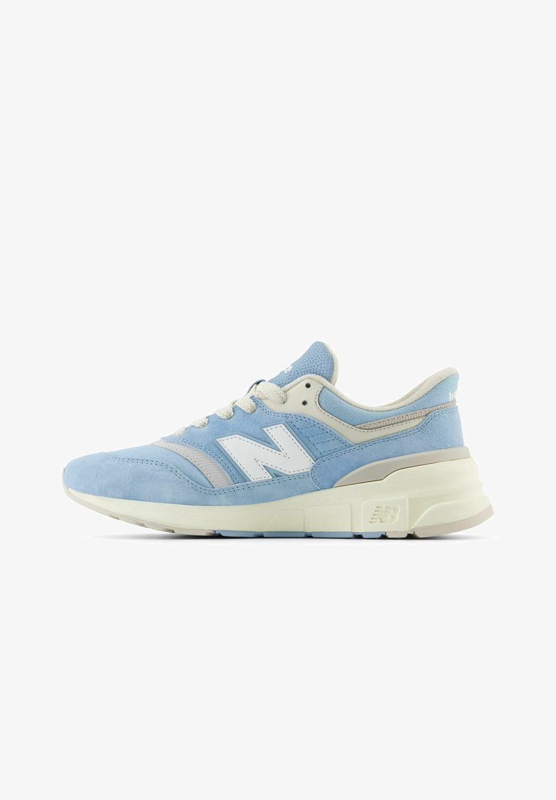 Baskets New Balance bleu clair et beige avec lacets blancs et semelle rembourrée, vues de profil sur fond blanc.