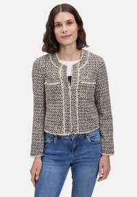 Krótka, przycięta kurtka z teksturowanego materiału tkane, z czarno-beżowym wzorem w kratę, postrzępionymi brzegami i zapięciem na zamek z przodu.