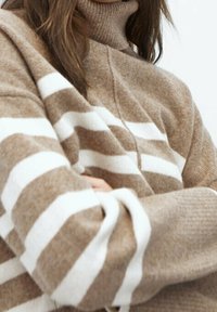 Brązowy i biały sweter z golfem w paski, wykonany z miękkiego materiału, z szerokimi poziomymi paskami i luźnym krojem.