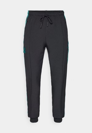 Pantalons de sport noirs avec une taille à cordon de serrage, poches latérales, rayures d'accent teal et poignets côtelés. Présente un patch logo texturé sur le côté.
