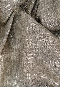Metallischer Stoff mit strukturiertem Gewebe, der eine Mischung aus Silber- und Goldtönen aufweist. Die Oberfläche hat einen subtilen Schimmer und fließende Drapierungen.