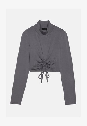 Maglia grigia a maniche lunghe e cropped con collo alto. Presenta dettagli arricciati con lacci regolabili all'orlo per un aspetto aderente.