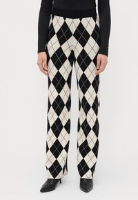 Hooggewaisted zwart-wit argyle-gepatenteerde broek met een zachte textuur, voorzien van een elastische tailleband en rechte pijpen.