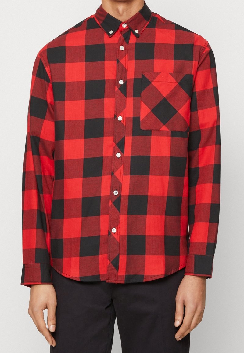 Camisa de manga larga de cuadros rojos y negros hecha de algodón, con cuello abotonado, bolsillo frontal y botones blancos.