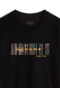 Sort bomulds-t-shirt med et horisontalt grafisk mønster i camouflage og "VANS" i gult, samt "SINCE 1966" nedenfor logoen.