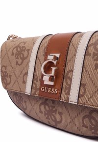 Borsa a tracolla marrone con pattern, rifinita con dettagli in pelle, presenta un grande logo metallico e strisce bianche. Il materiale sembra texturizzato e resistente.