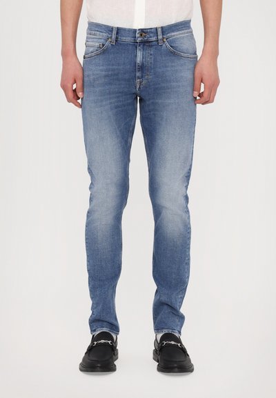 Tmavě modré džíny slim fit se slabým vyblednutím, pěti kapsami a zapínáním na knoflík. V kombinaci s černými botami.