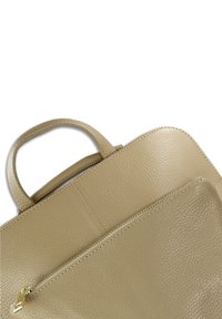 Sac à main en cuir beige avec une finition texturée, comportant une poche zippée et une poignée courte. Lignes épurées et détails de design minimalistes.