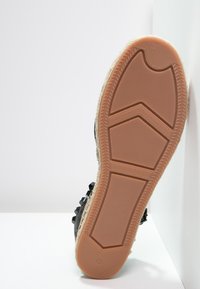 Sneaker musta tekstuuriga musta värvi, millel on kummist välispinna osa, millel on kuuekülgne mustrikujundus ja helepruun vaheosa. Rikkalikult dekoratiivsetest detailidest.