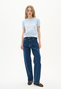 T-shirt azzurro chiaro a maniche corte abbinato a jeans blu scuro a vita alta e dritti, con ballerine a stampa leopardata. Design semplice e vestibilità casual.