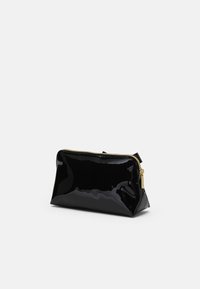 Bolso de maquillaje de charol negro con forma rectangular, herrajes de cremallera dorados y un acabado brillante. Cuenta con una base plana para mayor estabilidad.