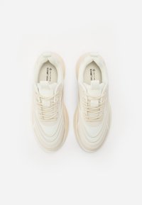 Beige veganske sneakers med lagdelt teksturdesign, rund tå og snørebånd. Har en blød stofoverdel og gummisål for godt greb.