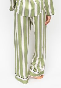Groene en wit gestreepte pyjama set met wijde broekspijpen. Bevat een soepele stof, contrasterende zwarte rand aan de zoom en een ontspannen pasvorm.