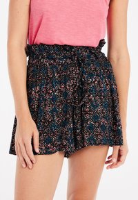 Shorts noirs avec un motif floral en bleu, rose et blanc. Dotés d'une taille élastique froncée et d'un lien en tissu à l'avant.