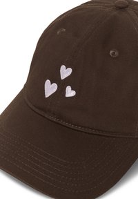 Casquette de baseball marron foncé avec trois petits cœurs blancs brodés sur le panneau avant au-dessus de la visière.