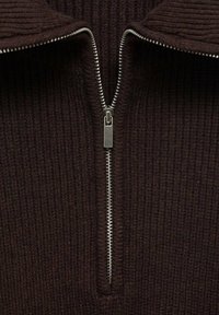 Maglione marrone a coste con colletto alto e zipper argento. Presenta un tessuto testurizzato e un design pulito e senza cuciture incentrato sulla zip.