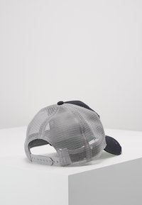 Graue Netz-Trucker-Kappe mit einem marineblauen Frontpanel, gebogenem Schirm und verstellbarem Kunststoffsnapverschluss. Mit einem gestickten Logo auf der Vorderseite.