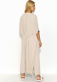 Beżowa długa sukienka z rękawami kimono, z wiązanym pasem i bocznymi rozcięciami. Wykonana z lekkiego materiału o gładkiej teksturze.