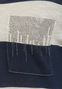 Maglione a righe navy e crema realizzato in maglia con tasca in strass metallici e design a cascata. Texture morbida e vestibilità casual.