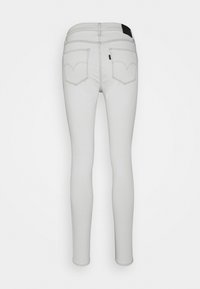 Jeans skinny en denim gris clair avec une texture lisse. Dispose de deux poches arrière avec un léger design en V sur les coutures et une étiquette noire à la taille.